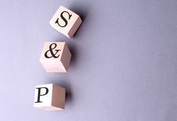 S and P word on wooden block on gray background