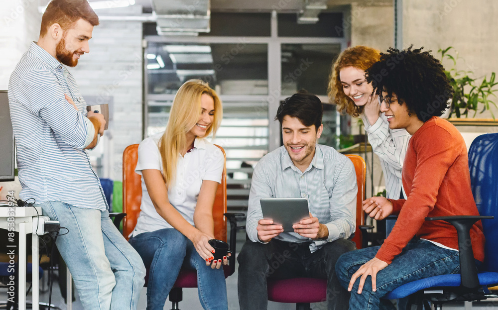 Aufkleber A diverse group of individuals seated around a wooden table, engaged in discussion and interaction while looking at a digital tablet placed in the center of the table.