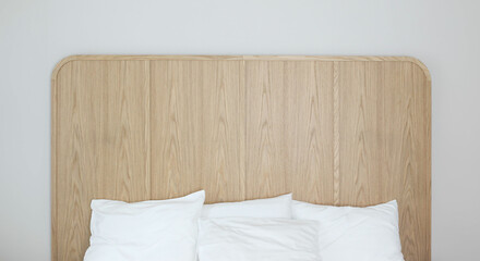 Obraz premium Modern luxurious bedroom with large empty double bed. White linens, pillows. Comfortable sleep. Oak wooden headboard. Grey wall background. Trendy elegant interior. Hotel, accomodation concept.