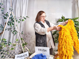 Middle-Aged plumb Woman Sorting Belongings With KonMari Method. Mature senior woman categorizes items into keep and discard piles