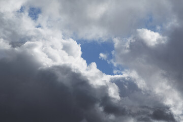 A gap in dense clouds through which the blue sky is visible