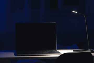 Black laptop screen in a dark room at night.