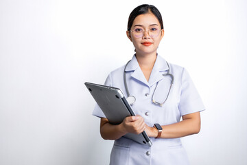 Young nurse in glasses with stethoscope on her shoulder holding a laptop computer isolated on gray background.