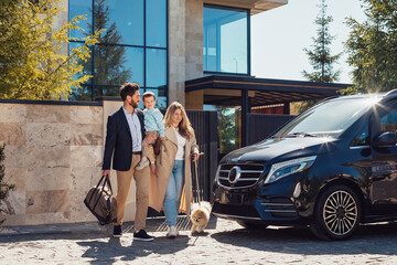 A young family with their son and dog and luggage going by car on vacation for the weekend