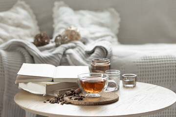 Home composition with a cup of tea, books and candles in the room.