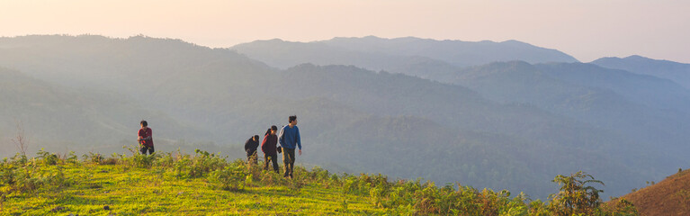 Obraz premium Group of Trekkers having fun in success pose with raised arms on mountain top. Web banner size.
