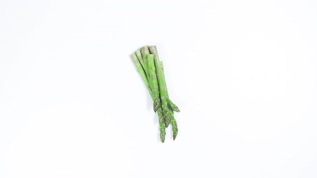Green and purple vegetables appear on a white background. Asparagus, lettuce, cucumbers, peppers, eggplant and avocado. Proper nutrition. Vegetarianism and veganism concept.