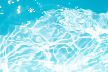 Blue water with ripples on the surface. Defocus blurred transparent blue colored clear calm water surface texture with splashes and bubbles. Water waves with shining pattern texture background.
