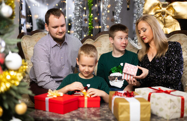 Children and parents give each other gift boxes during Christmas or New Year celebrations at home
