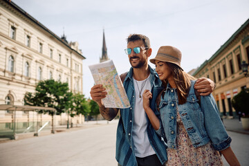 Happy travelers examining map while enjoying in  walk through  town.
