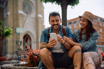 Happy couple of travelers using mobile phone in city. © Drazen