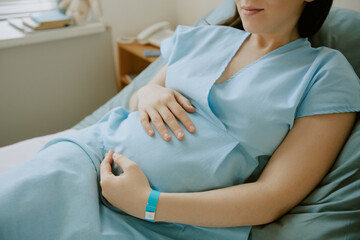 Obraz premium Pregnant woman lying on hospital bed and touching her tummy while she having contractions