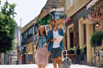 Cheerful couple of tourists walking in  city while traveling together.