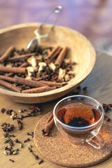 Cup of freshly brewed black tea, different types of spices on wooden table.