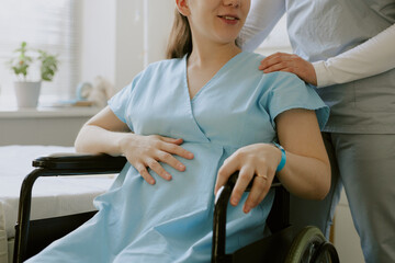 Pregnant patient caressing her belly and smile gently while nurse comforting her