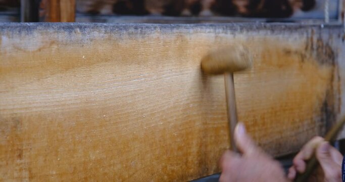 A man using two wooden mallets to beat a wooden semantron. A man using two wooden mallets to beat a wooden semantron