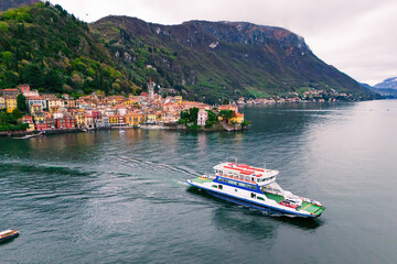 Fototapeta premium Aerial view of ferry boat with cars leaving the town of Varenna on Lake Como, Italy