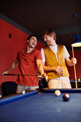 Friends play billiards in a casual setting, laughing and enjoying the game.
