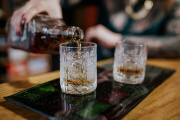 A close-up shot of a drink being poured into a glass, capturing the liquid in motion and highlighting the rich color and texture of the beverage.