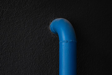 Photo of a blue pipe with a hydrant on a black wall