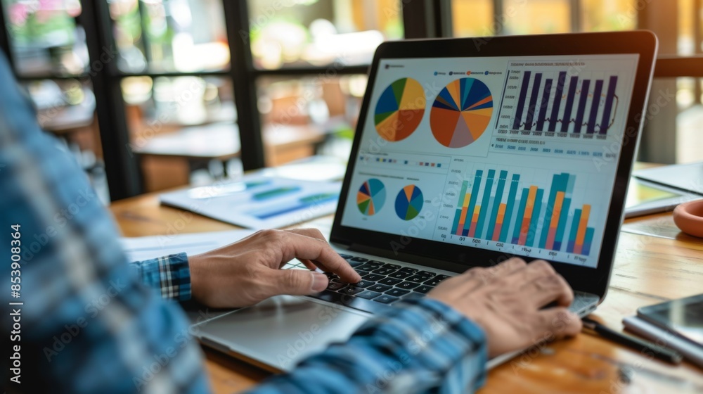 Leinwandbilder an overhead view of a financial analyst analyzing pie charts and graphs on a laptop screen, focusing