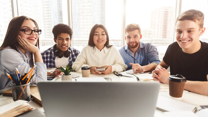 Online lesson. Students learning by laptop in university library, looking at screen together