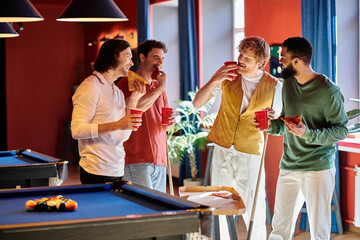 Friends gathered around a pool table, enjoying pizza and drinks.