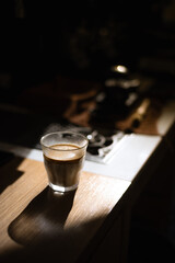 a glass of coffee sits on a table next to a stove.