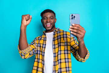 Photo of overjoyed glad man wear trendy checkered clothes use modern device isolated on cyan color background