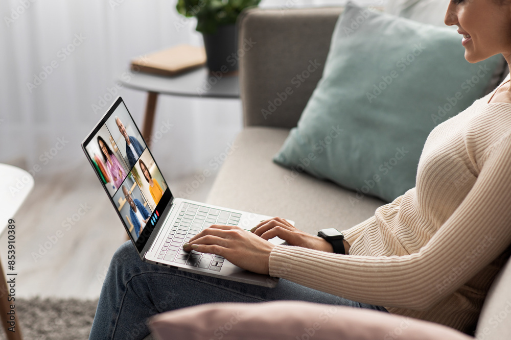 Poster a woman sits on a couch at home and uses a laptop computer to participate in an online video confere