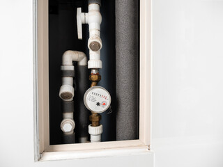 Water meter in box with pipes built into the wall . Water consumption measuring device