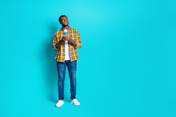 Photo of attractive cheerful man wear stylish clothes hold device look empty space isolated on cyan color background