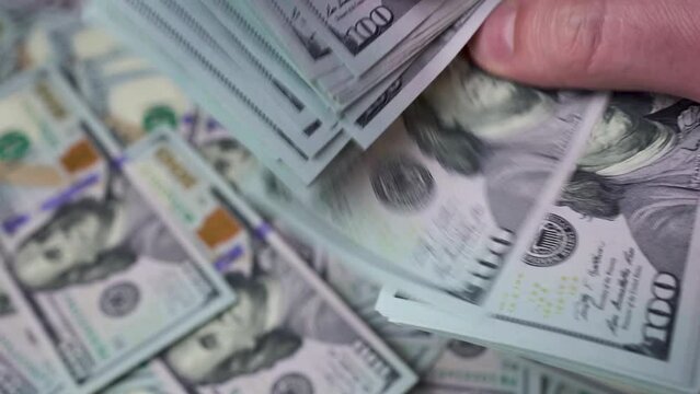 Man's fingers count a thick stack of American dollars. Concept of currency exchange, riches, money savings, profit, saving paper money. High quality 4k footage