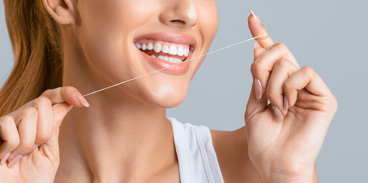 Cropped of a young woman flossing her teeth with a white floss. Her smile is bright and white, showing off her healthy and clean teeth. The importance of oral hygiene and good dental care.