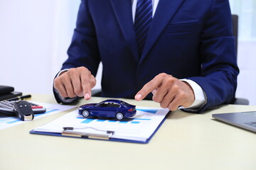 Car insurance documents or rental concept. A car broker helps his customers and explains the...