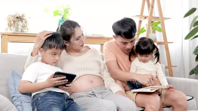 Young Asian parents help their children with homework. mom and dad teach daughter and son to draw and paint. Happy family spending free time together on holidays, activity at home.