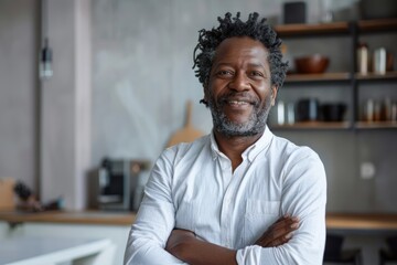 Portrait of a satisfied afro-american man in his 40s with arms crossed while standing against modern minimalist interior