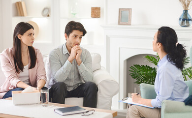A man and a woman are seated on a couch in a therapists office. The therapist is listening intently...