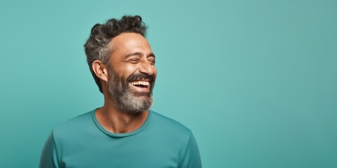 
Portrait photo of a happy Middle Eastern man, 46 years old, winking on a pastel teal background