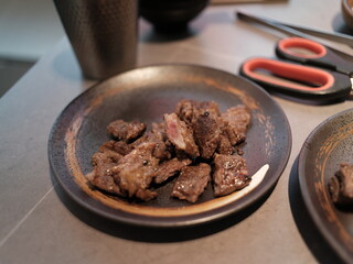 The image shows a close-up view of a plate filled with grilled meat pieces. The meat appears to be well-cooked with a slightly caramelized exterior, suggesting it has been grilled to perfection. 