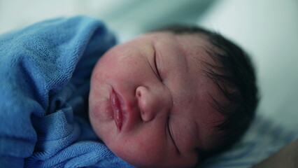 Close-up of newborn baby during first day of his life asleep after childbirth. Initial hours of infant's life sleeping