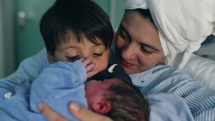 Family Welcoming Newborn at Hospital - Brother holding infant in arms as mother watches, Siblings Bonding for the First Time Post-Childbirth