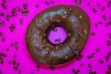Chocolate donut with chocolate sprinkles on a purple background.