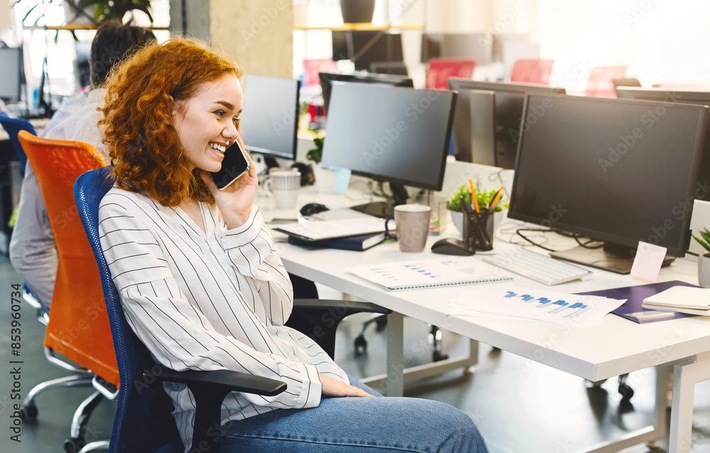 Poster a woman sitting at a desk, engaged in conversation on her cell phone. she appears focused and attent