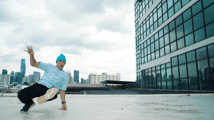 Stylish caucasian dancing man performing break dance at skyscraper. Portrait image of young happy...
