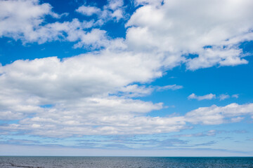 Numerous cloud formations with the blue sky background over the calm water of Lake Michigan in late April off the coast of Kohler-Andrae State Park, Sheboygan, Wisconsin