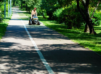 Lawnmower operator on empty morning park road backdrop