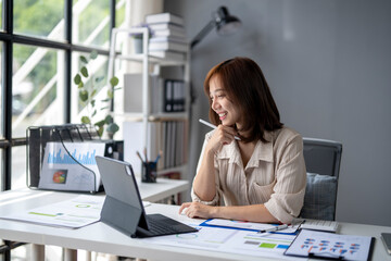 Obraz premium A woman is sitting at a desk with a laptop and a tablet