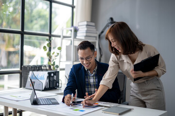 Fototapeta premium A man and a woman are sitting at a desk with a laptop and a tablet