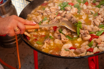 Hand of Woman Preparing Traditional Spanish Paella at an outdoor event